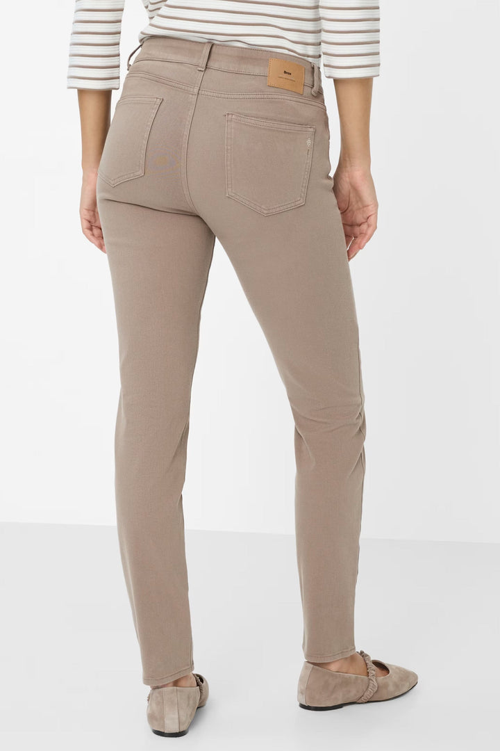 Femme portant le Pantalon Shakira ajusté beige, coupe slim fit, associée à un haut rayé et des chaussures plates, vue de dos.