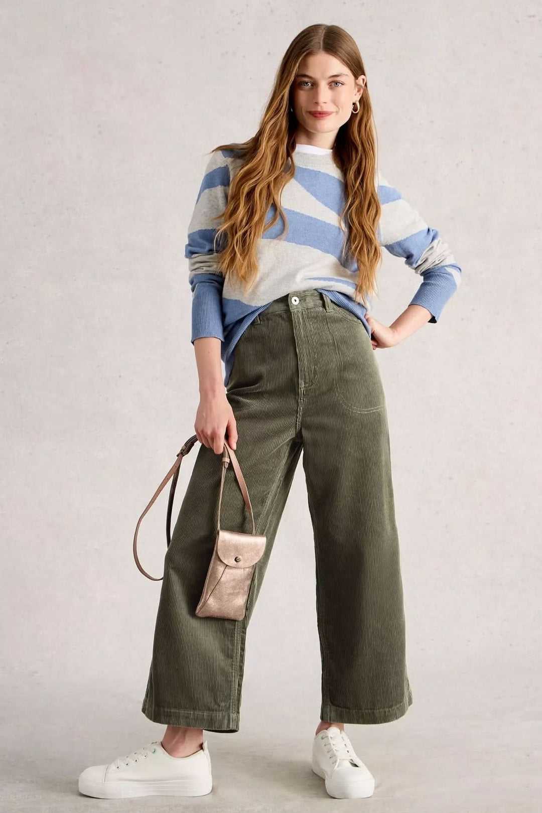 Femme portant le Pantalon Tia en velours côtelé avec coupe évasée, taille haute, style moderne et décontracté.