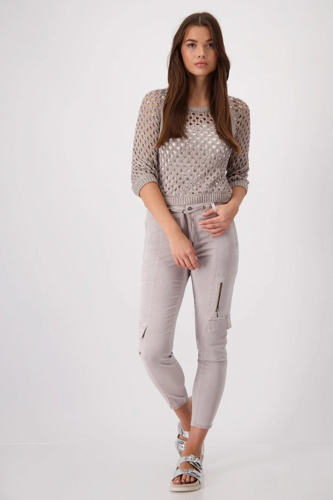 Femme portant un pantalon cargo en lyocell, associé à un pull en maille et des sandales, look moderne.