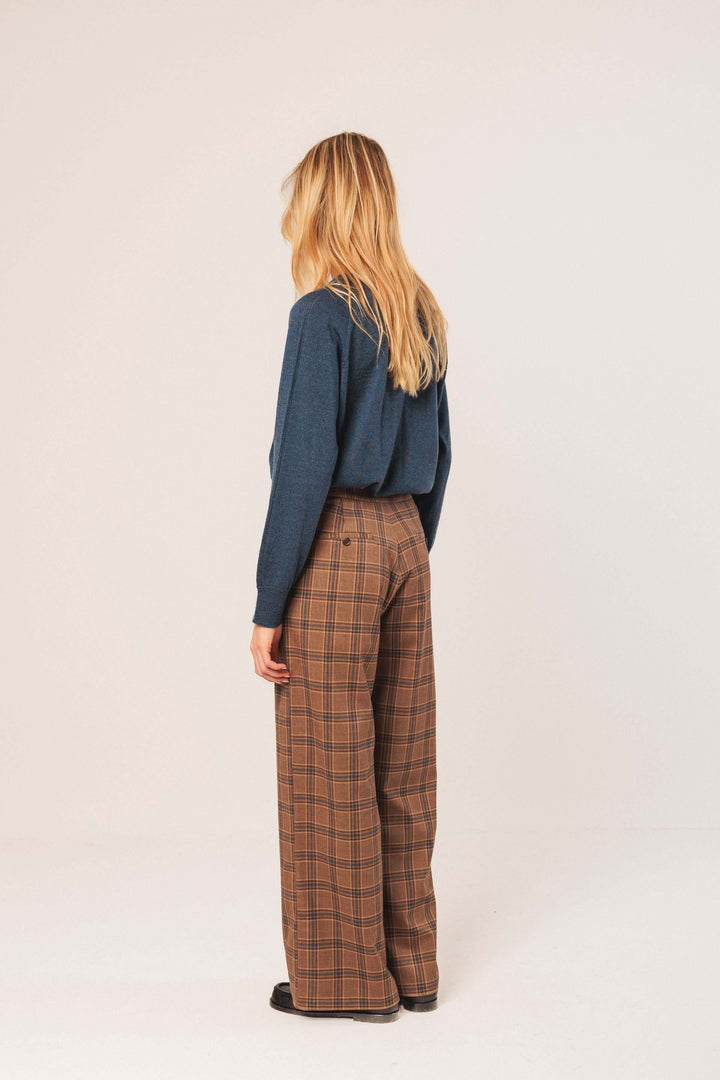 Femme portant un pantalon à carreaux taille haute avec coupe large, style élégant et confort moderne.