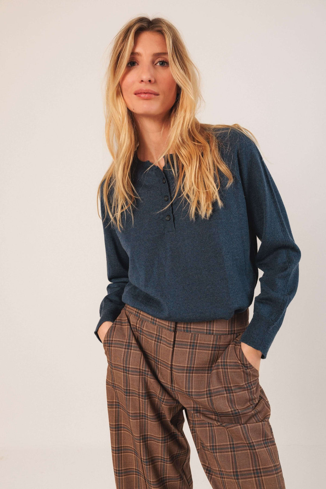 Femme portant un pantalon à carreaux taille haute avec une chemise bleue, mettant en valeur le style chic et classique du vêtement.