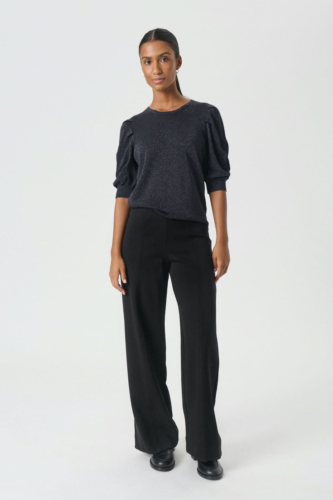 Modèle portant le Pantalon classique Vinda à jambe large, idéal pour le bureau et les sorties, avec une coupe fluide et une taille élastique.