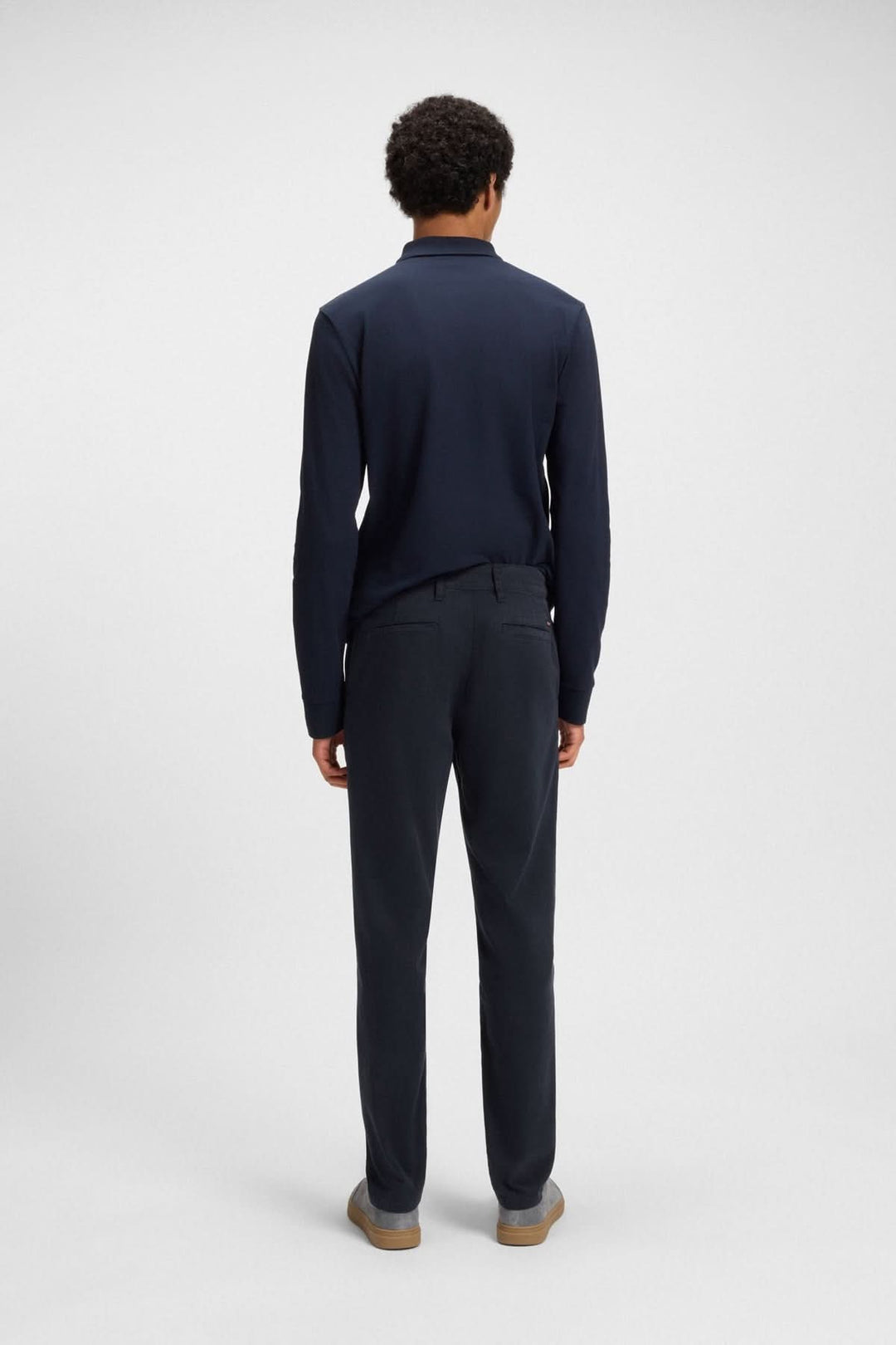Homme vu de dos portant un pantalon fuselé et un polo bleu marine, mix parfait de confort et d&