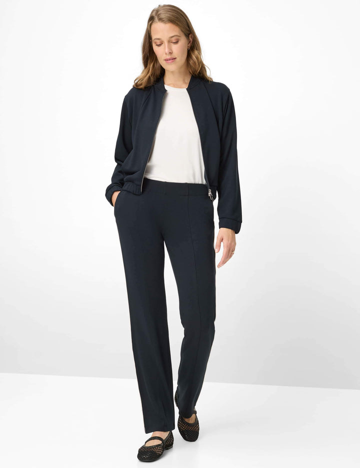 Femme portant un pantalon droit à bandes latérales MALIA avec un haut blanc et une veste noire.
