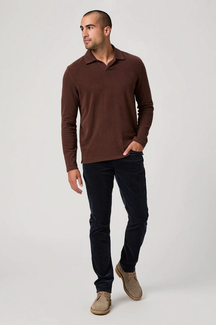 Homme portant un pantalon en micro corduroy noir, coupe ajustée, avec pull marron.