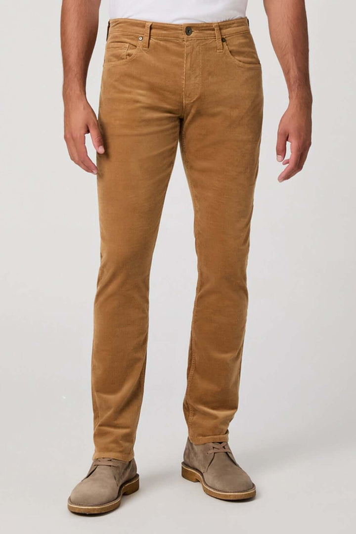 Homme portant un pantalon en micro corduroy marron, coupe ajustée et élégante, offrant confort et style. Décris moi le produit en français.