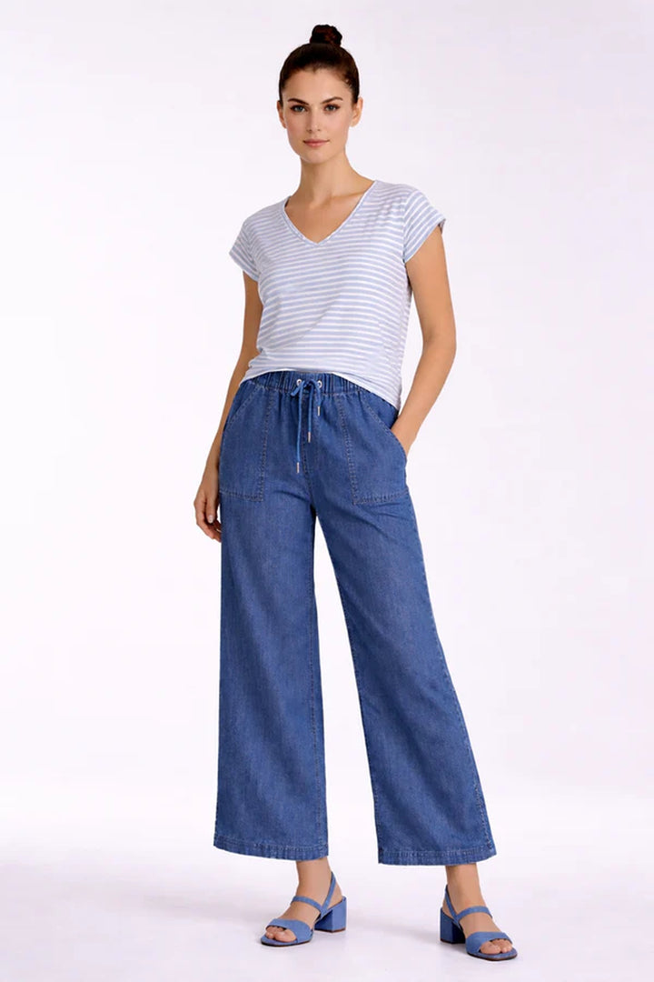 Femme portant un pantalon fluide taille élastique à cordon, coupe large et fluide, longueur cheville, avec poches appliquées.