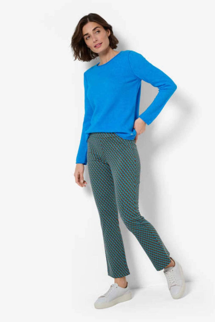 Femme portant pantalon imprimé Malou et pull bleu, avec baskets blanches, style décontracté et tendance.