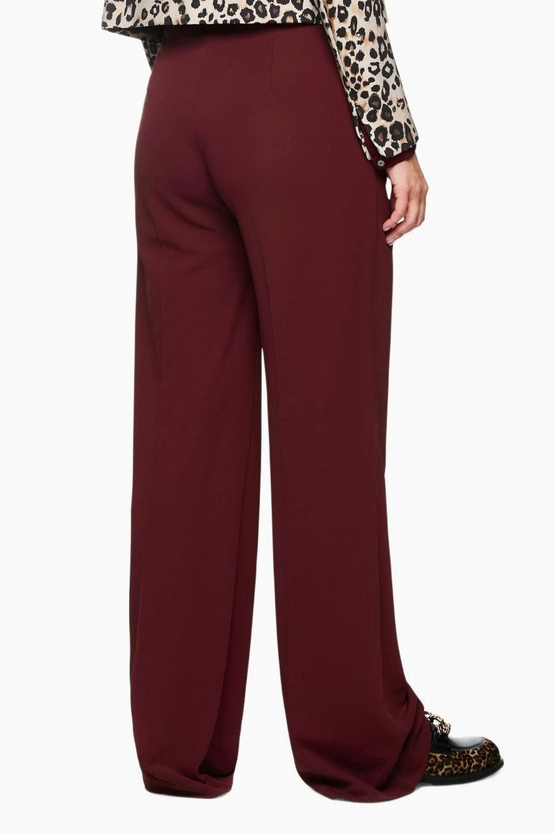 Pantalon jambes larges en matière fluide avec taille haute et plis, porté avec une blouse imprimée léopard, vue de dos.