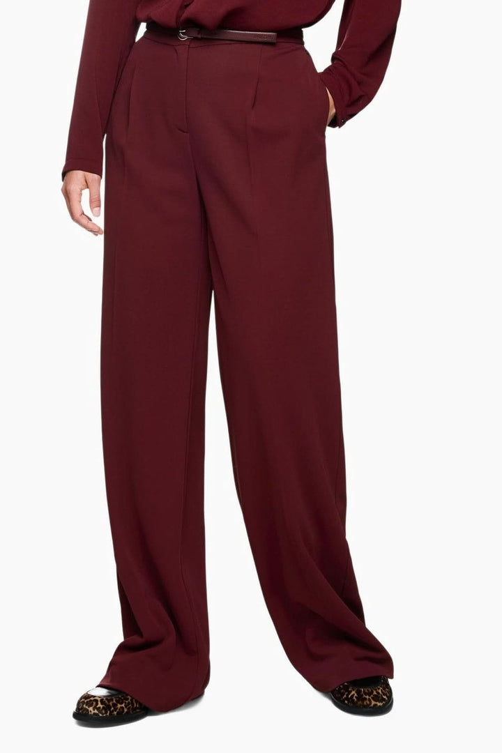 Pantalon jambes larges élégant en matière fluide, taille haute avec plis, combine confort et style raffiné pour une silhouette structurée.