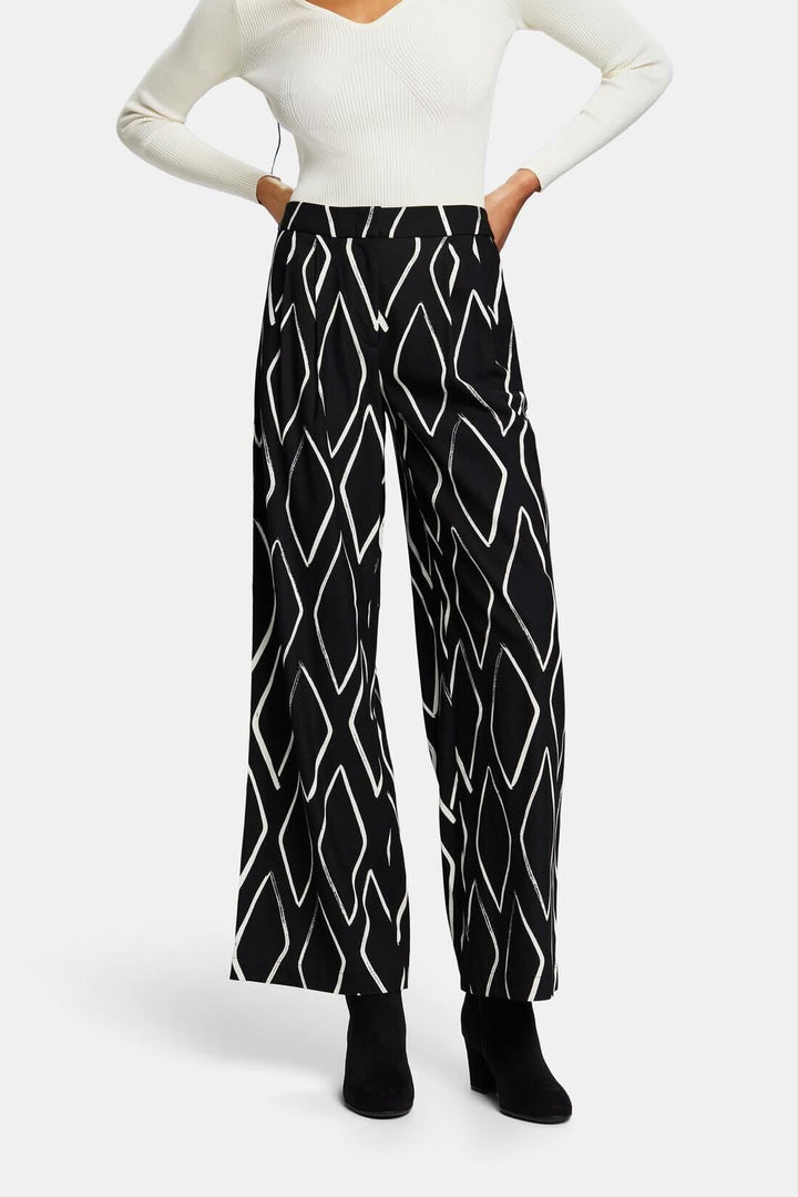 Pantalon large à enfiler avec imprimé losanges noirs et blancs, taille élastiquée, porté avec un haut blanc.