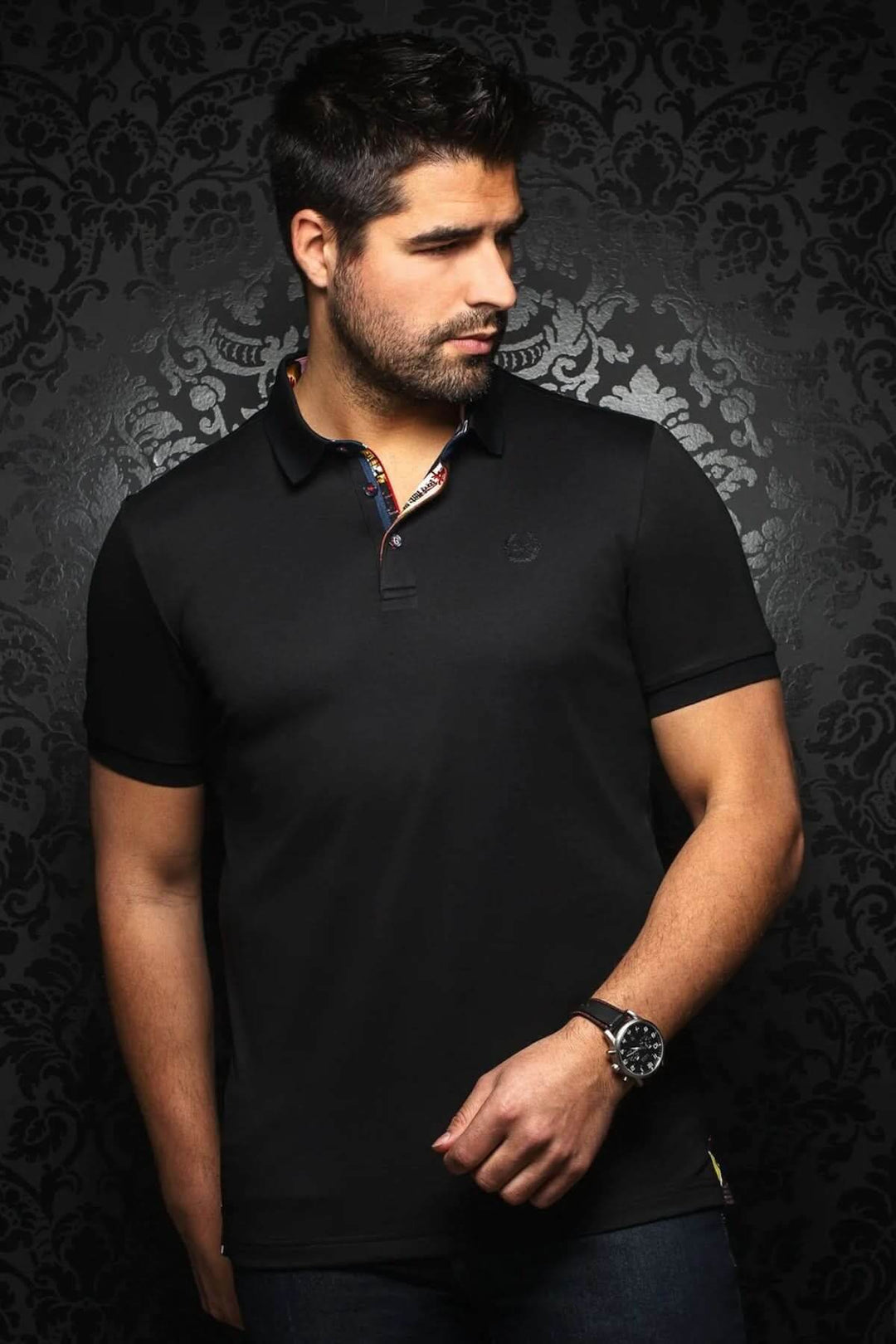 Homme portant un polo noir élégant avec col contrastant et broderie discrète sur fond sombre.