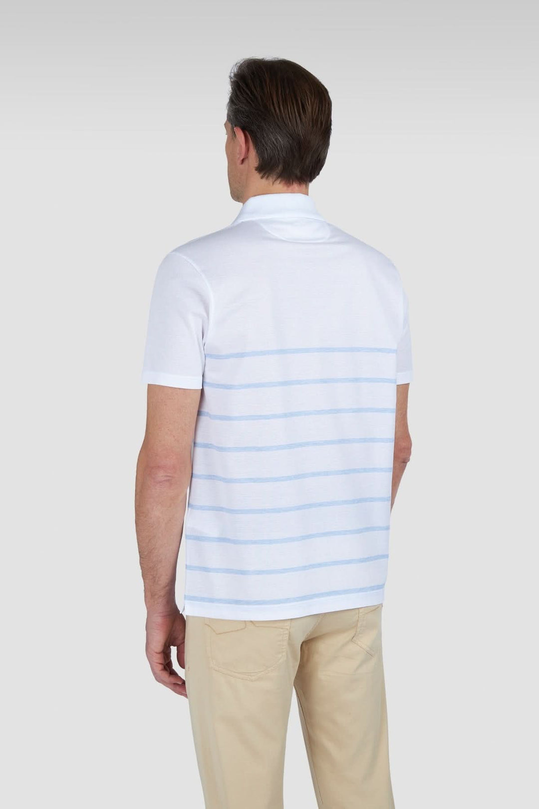 Homme de dos portant un polo en coton piqué à rayures dégradées, style décontracté.