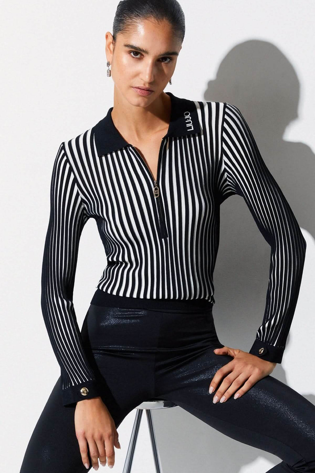 Femme portant un polo en maille côtelée à demi-glissière avec col structuré et manches longues, ajoutant une touche sportive et élégante.