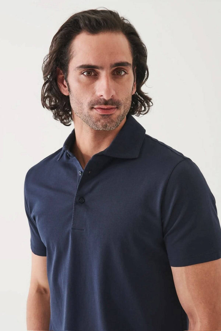 Homme portant un polo à manches courtes, tissu doux, coupe fluide, couleur bleu marine, style chic et décontracté.