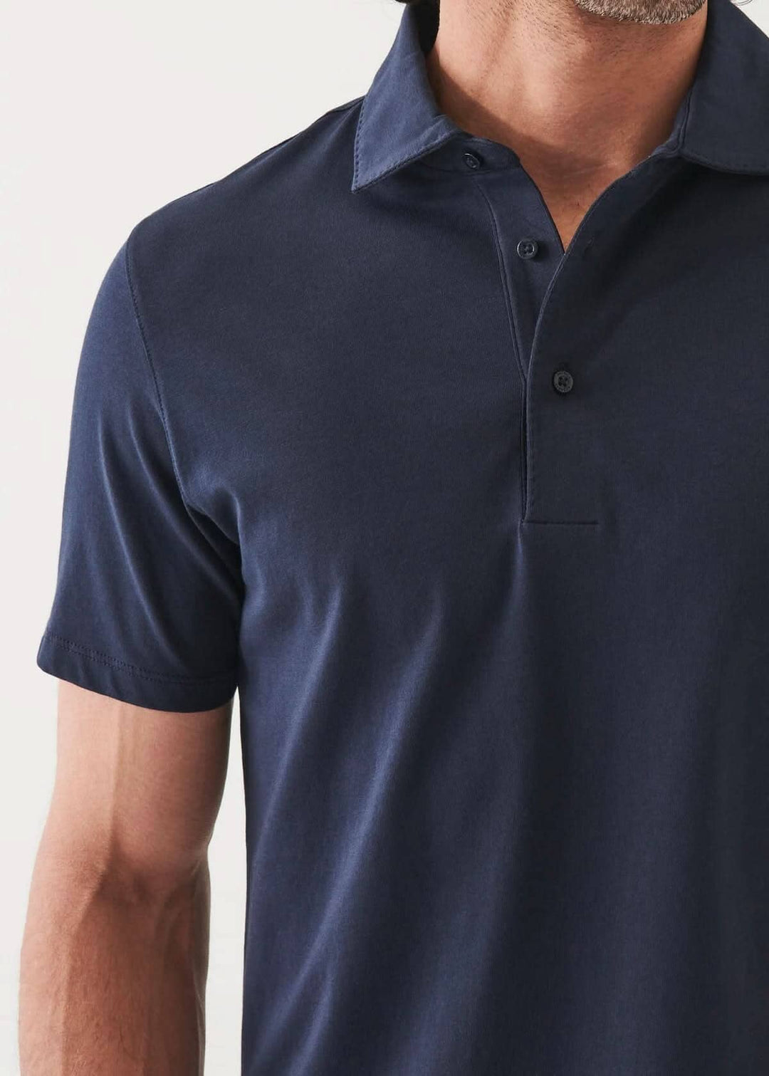 Polo à manches courtes de couleur bleu marine, avec col classique et patte de boutonnage à deux boutons.