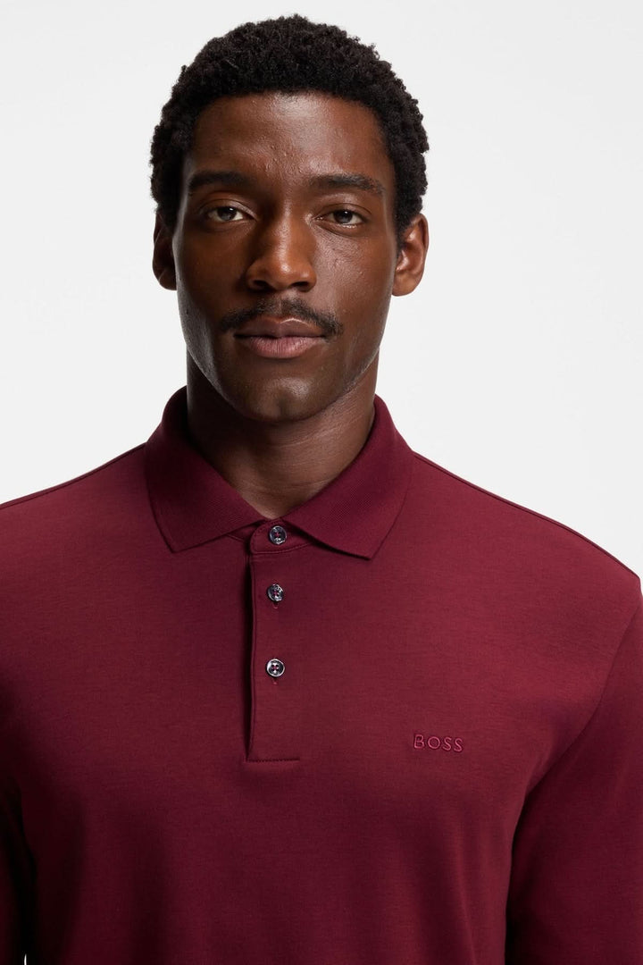 Homme portant un Polo manches longues Pado BOSS de couleur bordeaux avec col plat et patte à trois boutons.