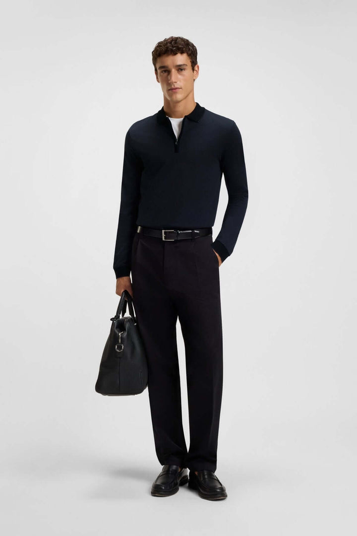 Homme portant un polo à manches longues avec fermeture éclair chic et élégant, idéal pour un style contemporain et raffiné.