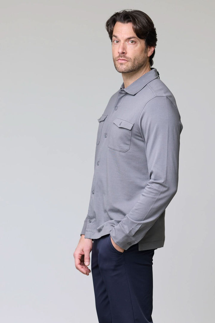 Homme portant un Polo à poches boutonnées gris, manches longues, col chemise, look décontracté chic.