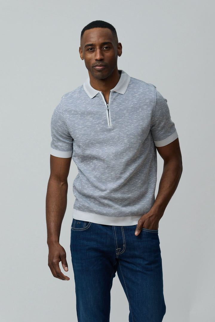 Homme portant un polo texturé à fermeture zippée gris en coton peigné avec manches courtes, style décontracté et élégant.
