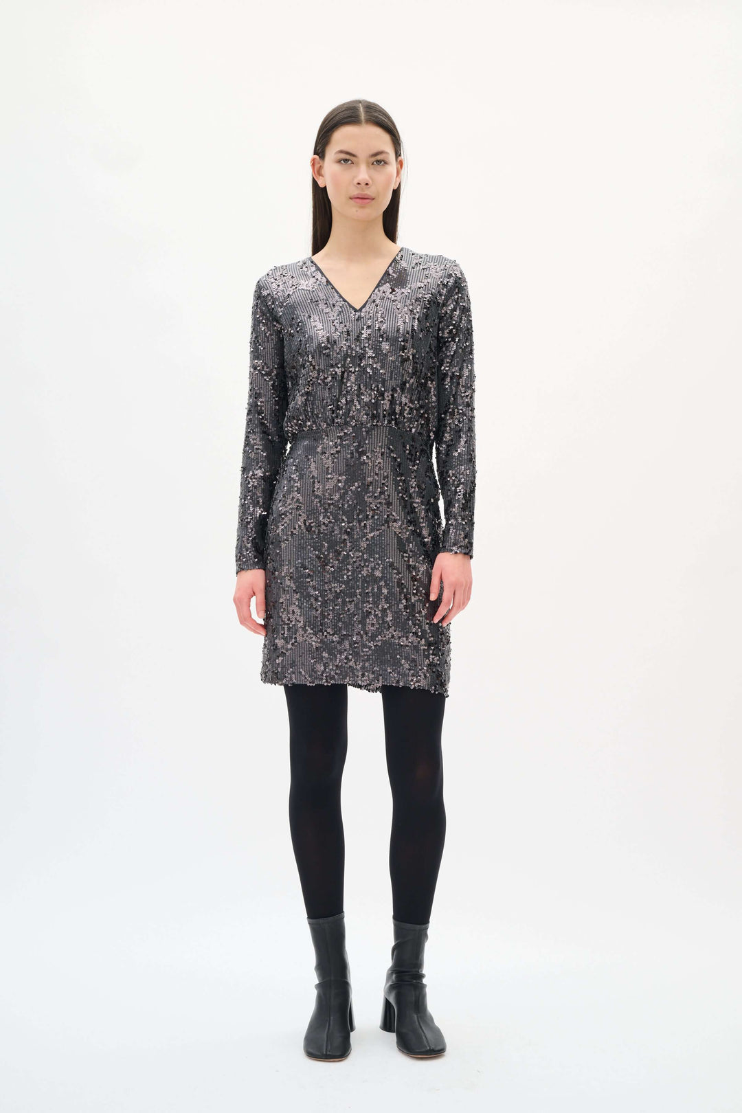 Femme portant la Robe Kimba à paillettes à manches longues avec col en V, coupe élégante pour soirées festives.