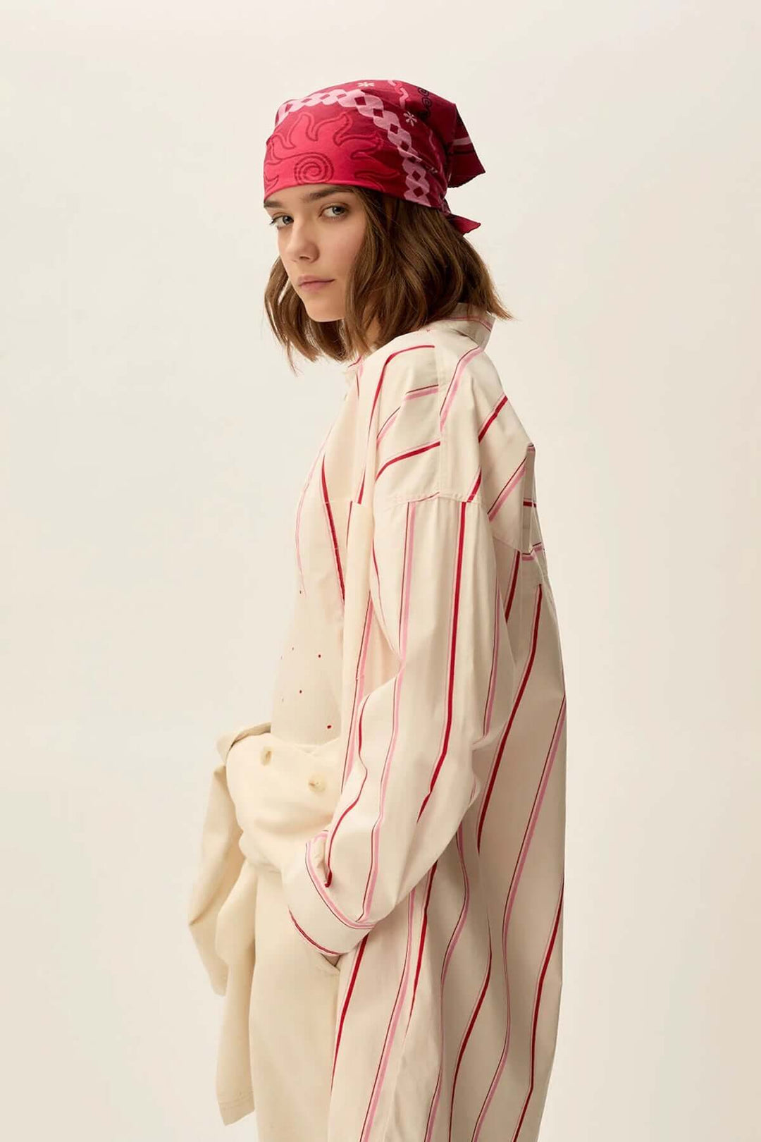 Femme en robe longue rayée avec un bandeau rose, style oversize, prête à superposer avec différentes tenues.