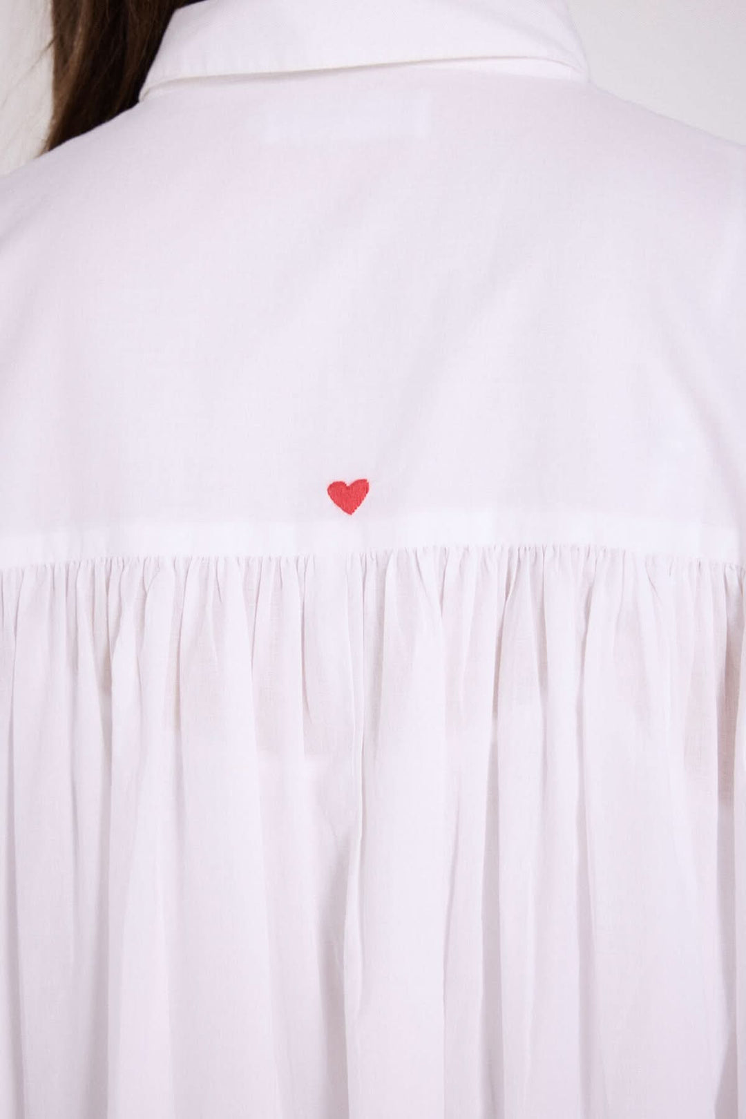 Détails de la robe chemise Gabriela, montrant le plissé arrière et un petit cœur rouge brodé.