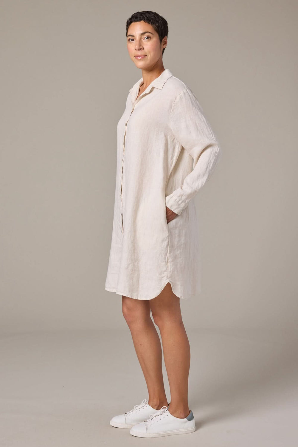 Femme portant une robe chemise en lin à manches longues, coupe droite et décontractée, idéale pour un look épuré.