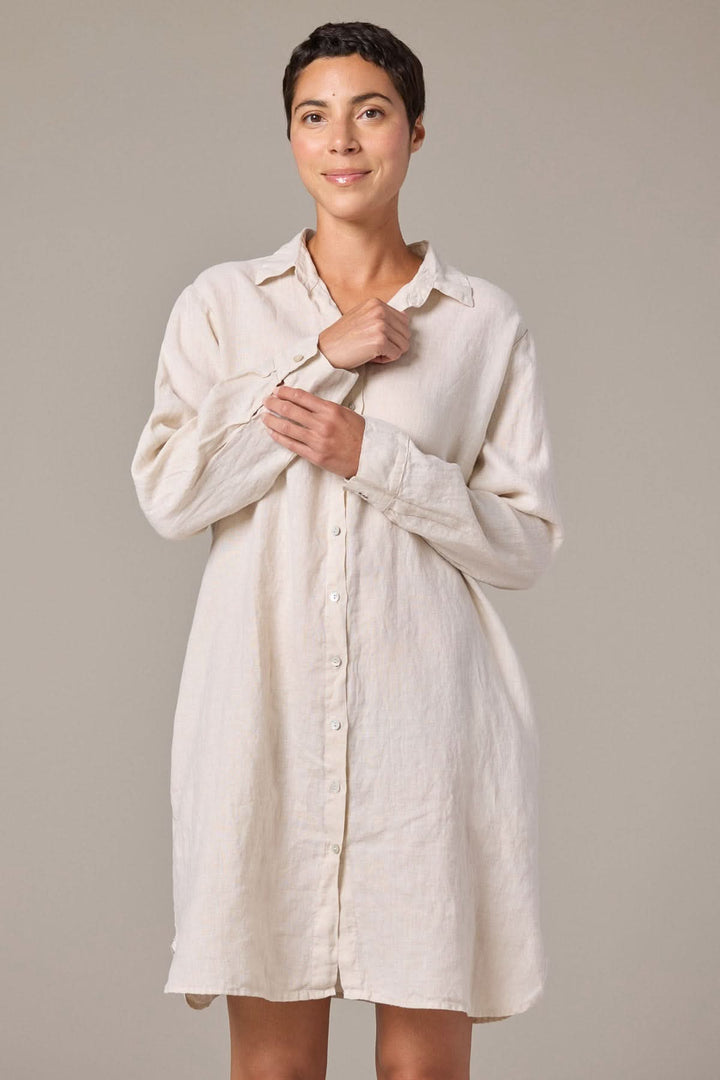 Femme portant une robe chemise en lin à manches longues avec coupe droite et col classique boutonné.