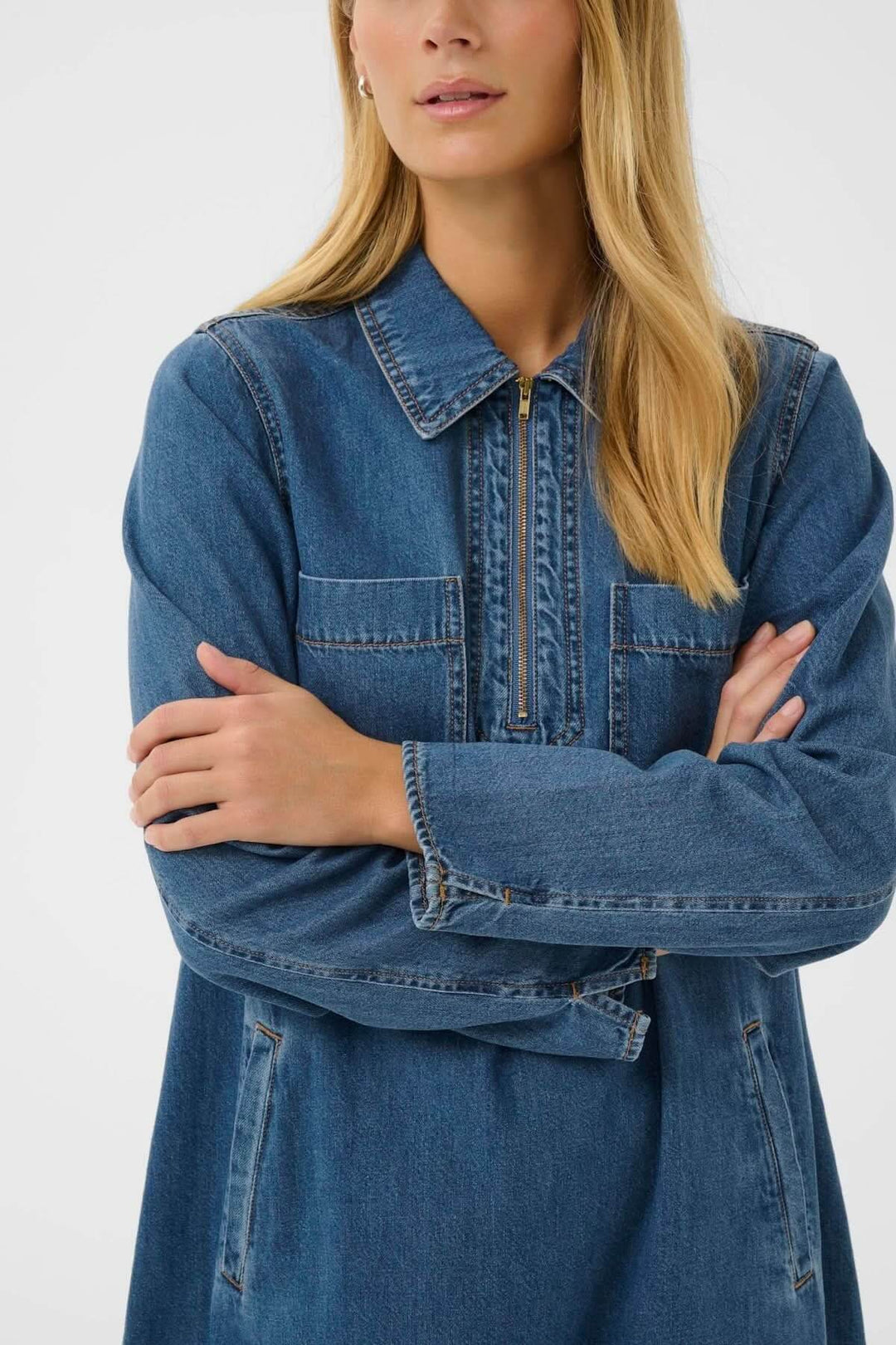 Robe en denim avec col chemise zippé, coupe droite ample, et longueur au-dessus du genou pour un style décontracté et moderne.