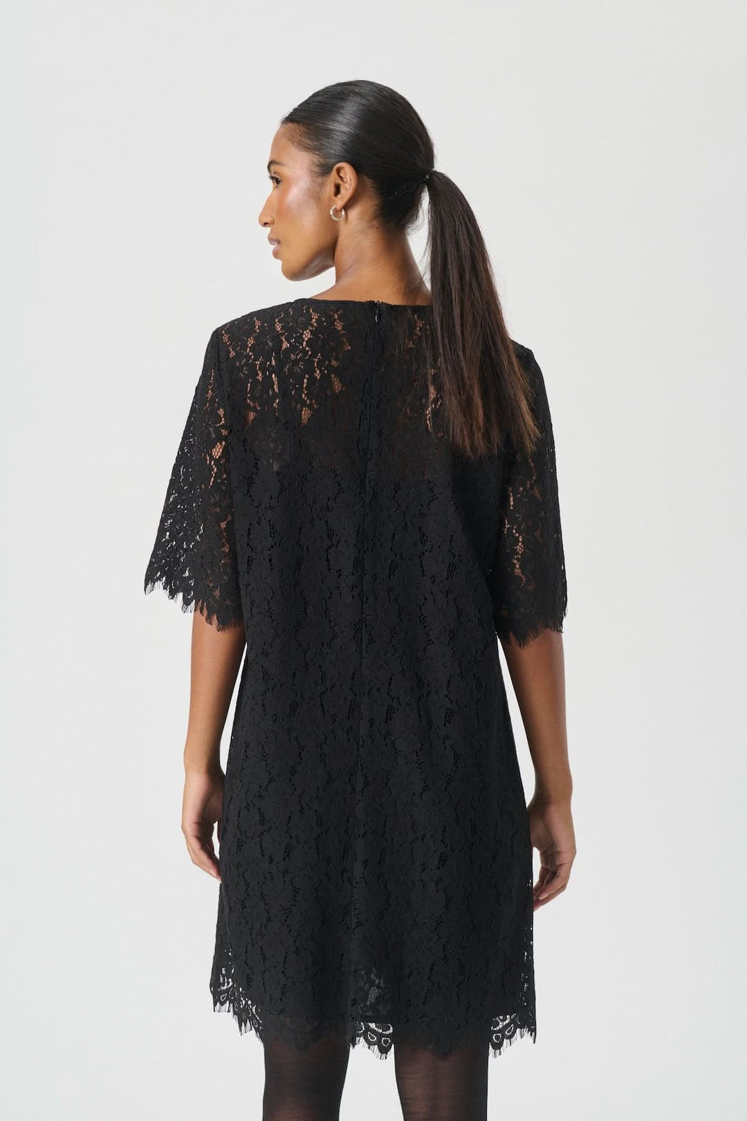 Femme portant une Robe en dentelle Vienne noire avec manches semi-transparentes et coupe évasée, vue de dos.