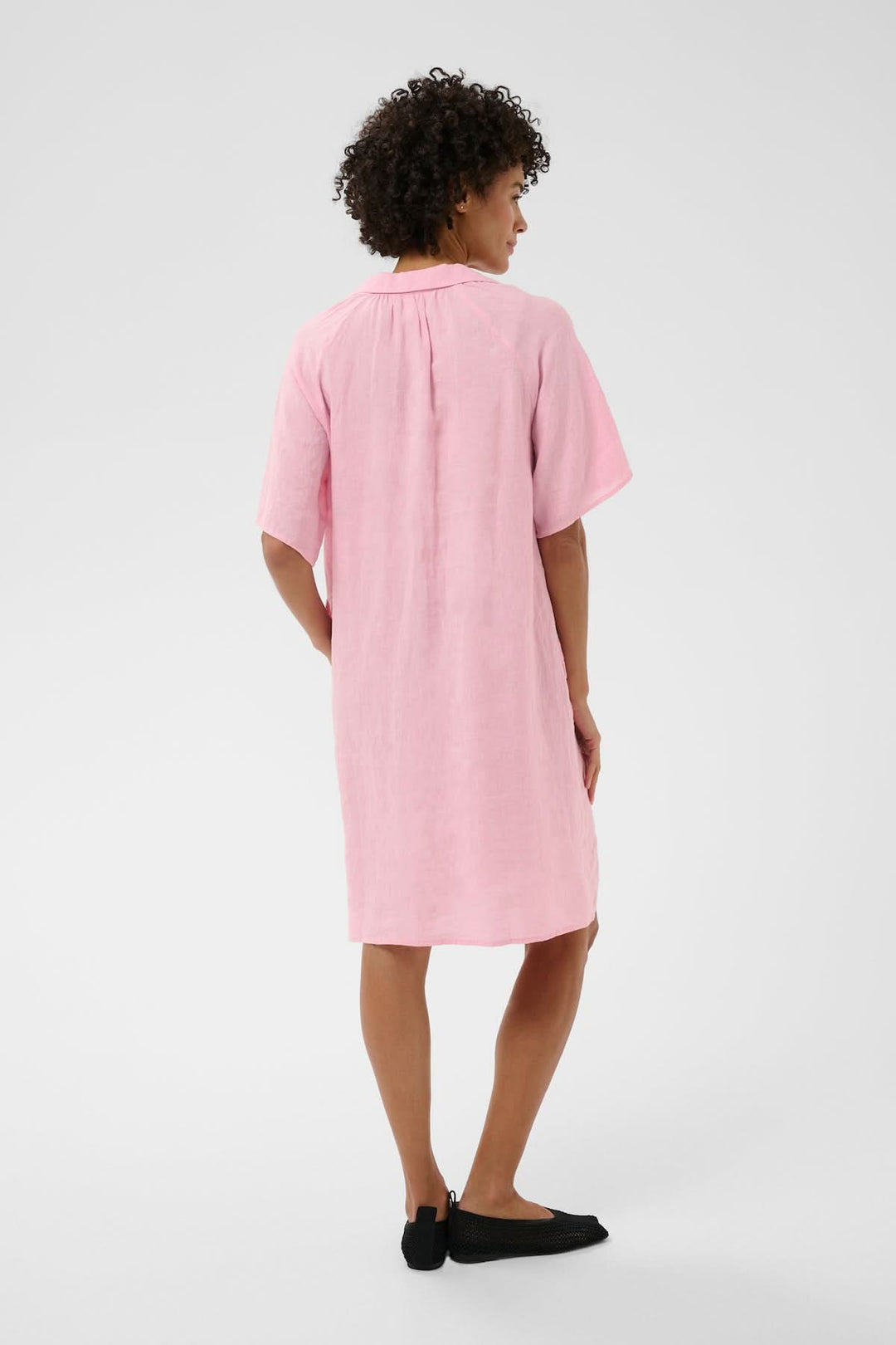 Femme portant la Robe en lin Ayla rose avec coupe droite et détails plissés, vue de dos.