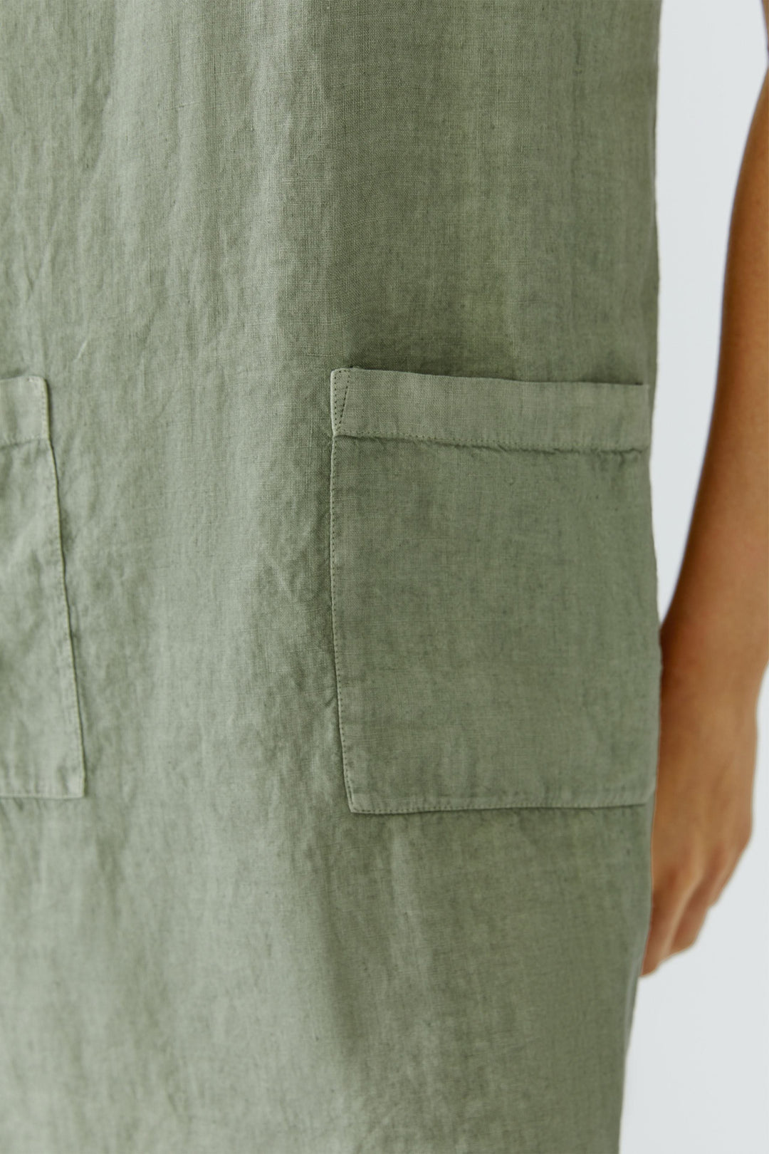 Robe en lin à manches courtes avec poches plaquées à l’avant et tissu vert, montrant les détails et la texture de la matière.