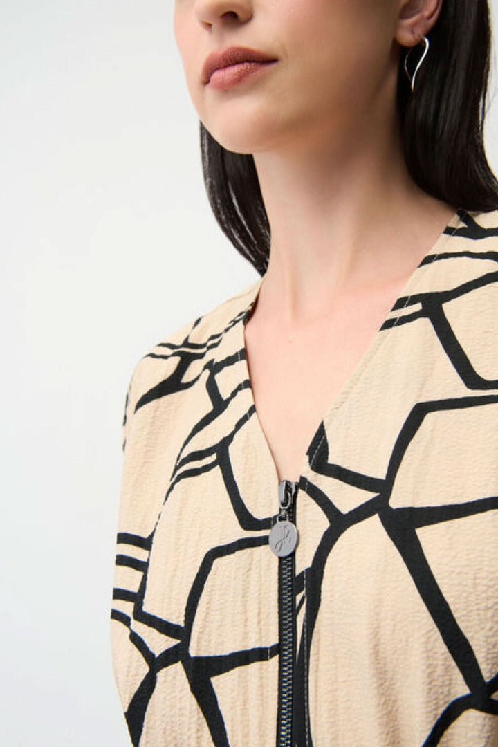 Femme portant une robe imprimée à taille marquée avec un motif graphique et zip, soulignant une silhouette féminine.