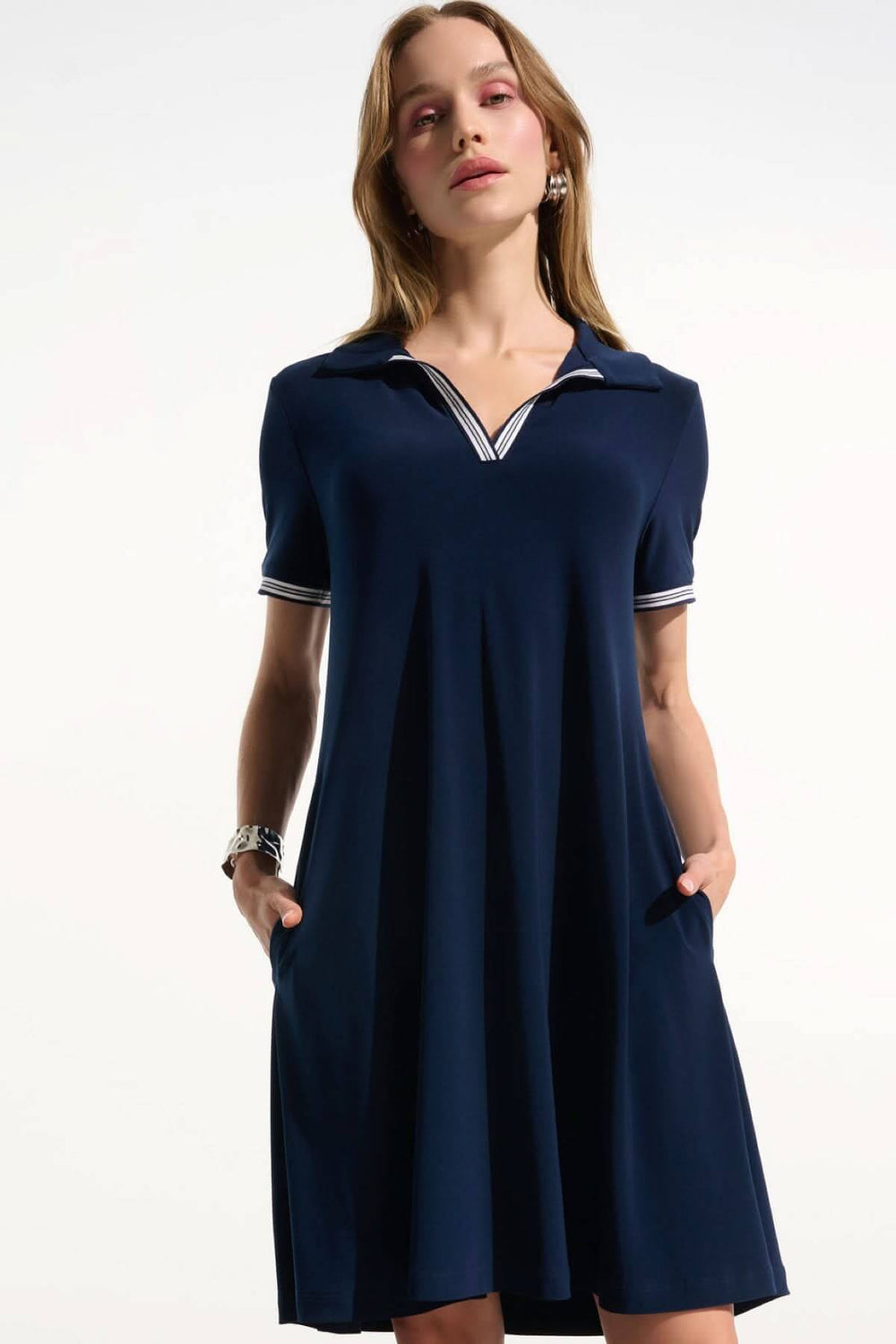 Femme portant une robe polo à col contrasté bleue, coupe ample et fluide, avec un col en V et bordures rayées, idéale pour l'été.