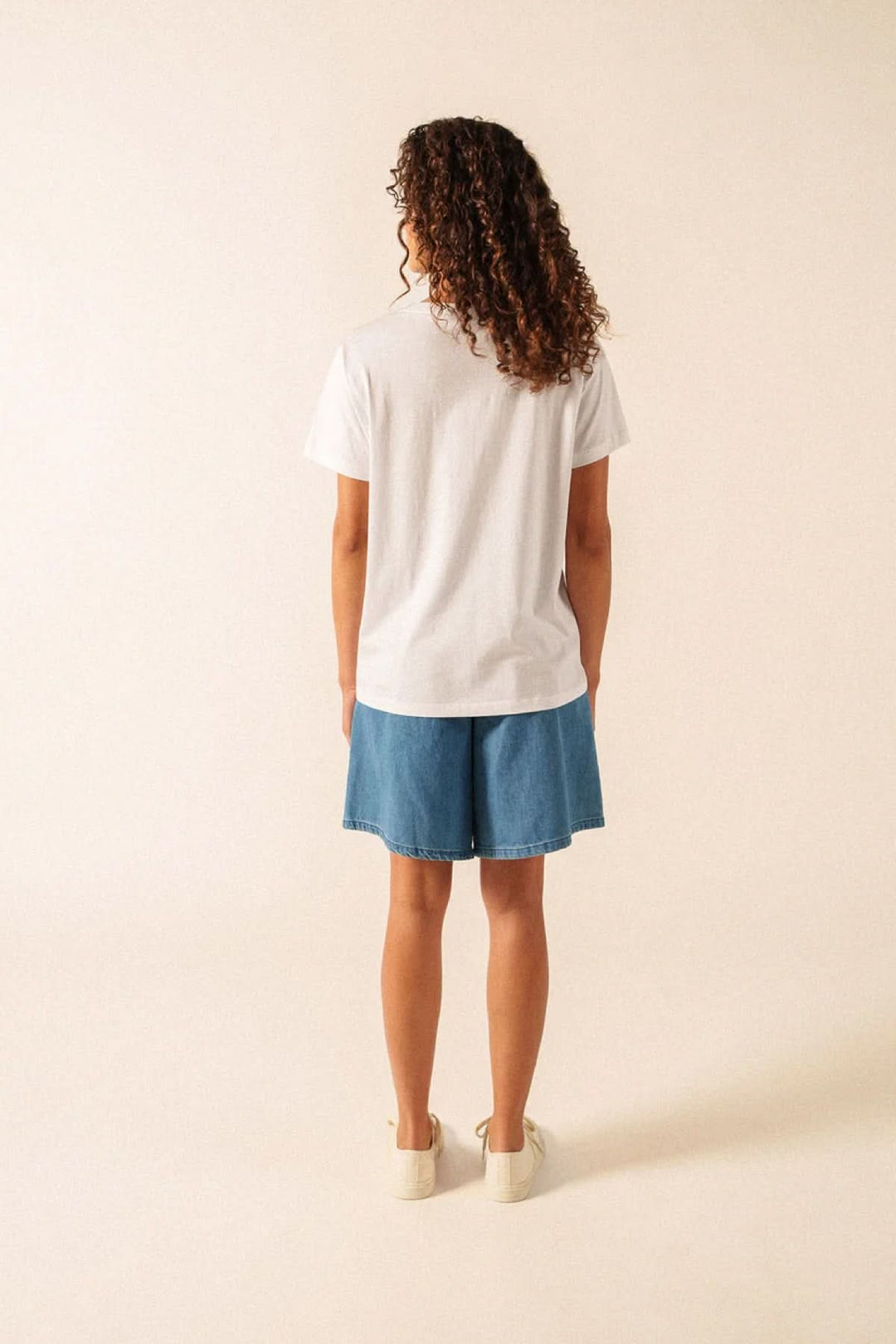 Vue arrière du T-shirt Léonore blanc porté avec un short en jean, mettant en valeur son design minimaliste et confortable.
