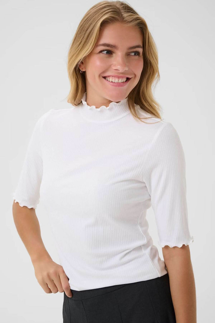 Femme portant le T-shirt Ribba à col montant, blanc avec maille côtelée et finitions festonnées, style chic décontracté.