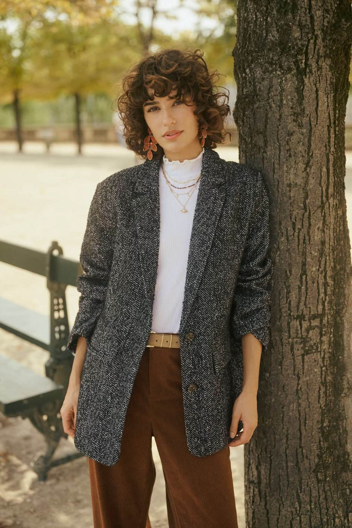Femme en veste grise devant un arbre dans un parc