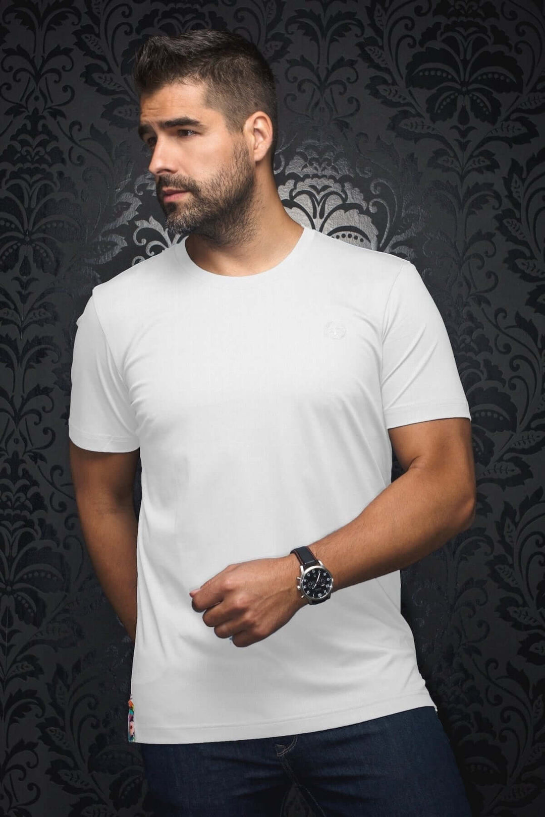 Homme portant un t-shirt blanc coupe ajustée avec écusson sur la poitrine et étiquette colorée à l'ourlet.