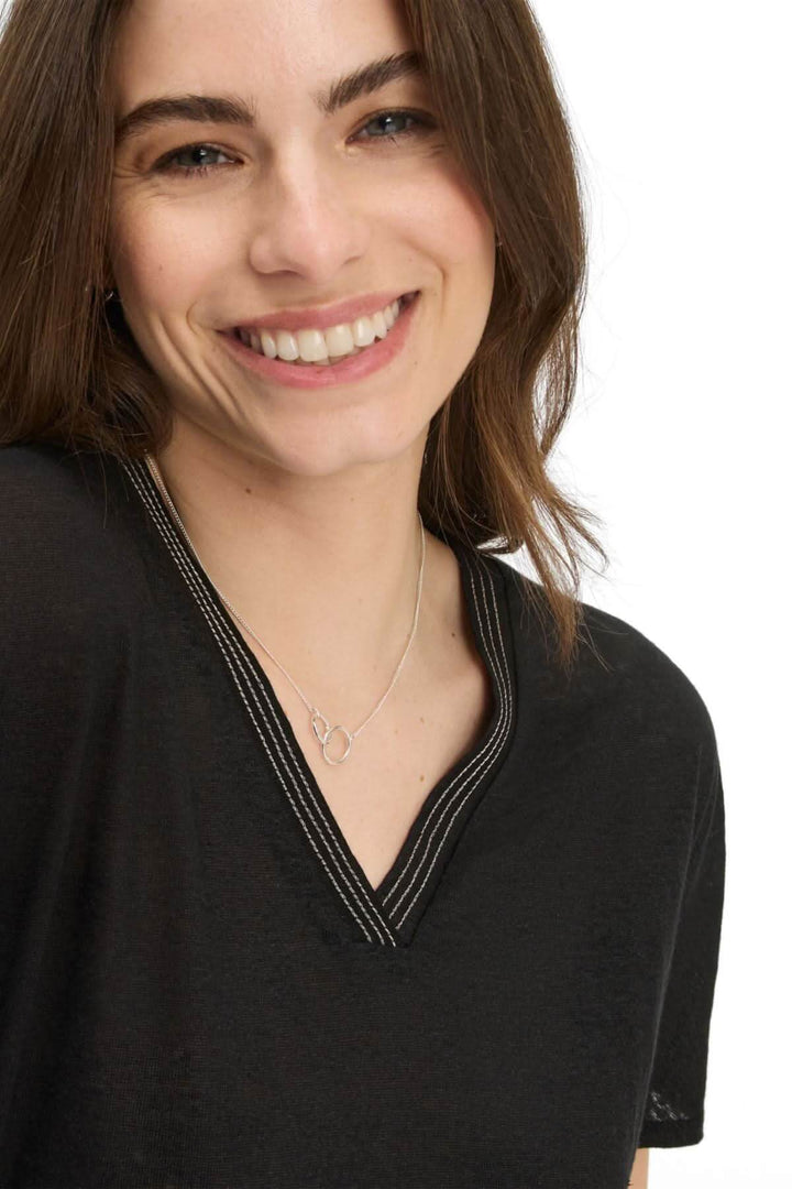 Femme souriante portant un T-shirt col V caelen en lin noir avec couture décorative.