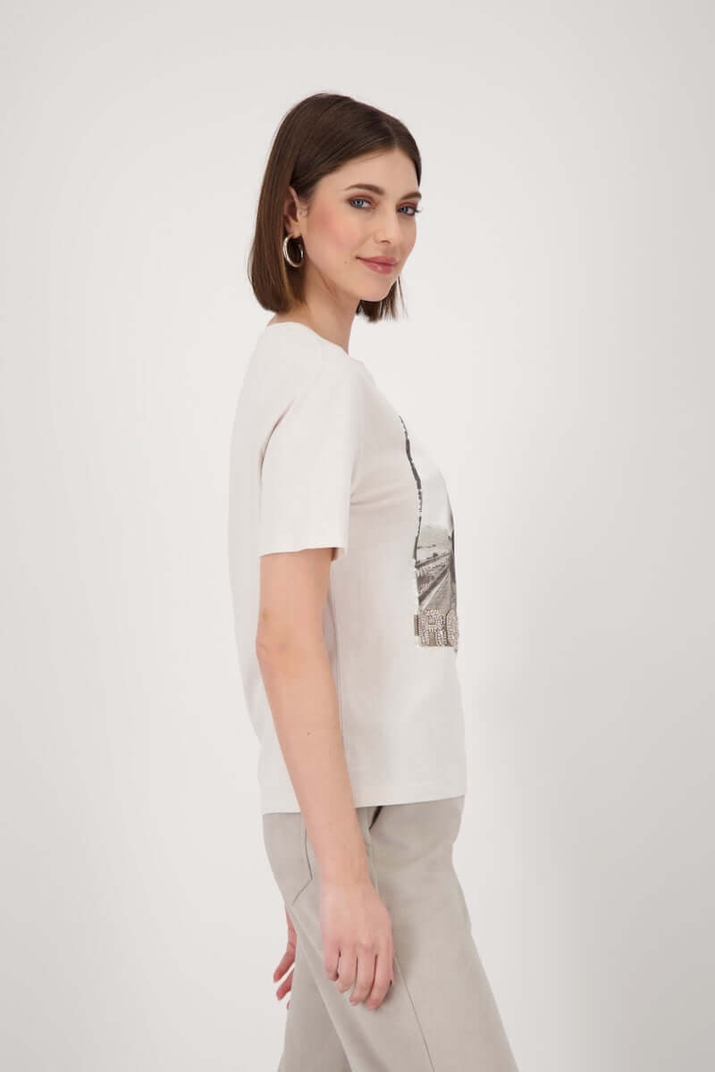 Femme portant un t-shirt imprimé avec motif « road trip », manches courtes et strass, style casual chic.