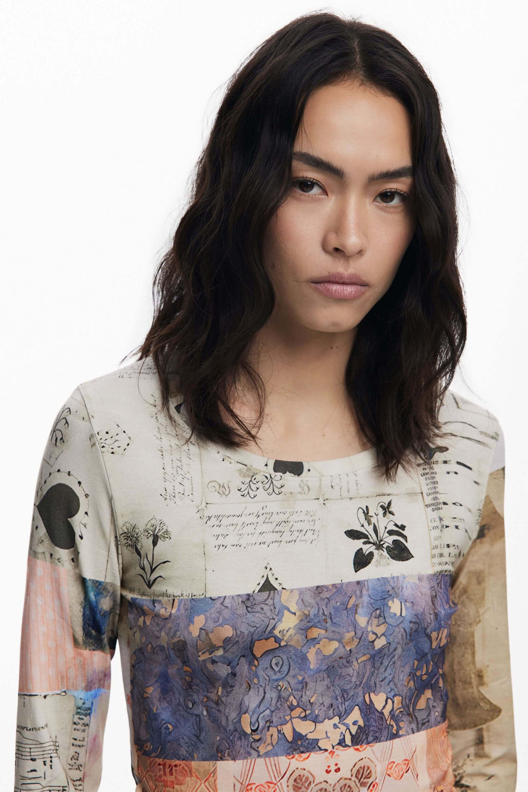 Femme portant un t-shirt imprimé patchwork avec imprimé artistique mêlant partitions et dessins botaniques.