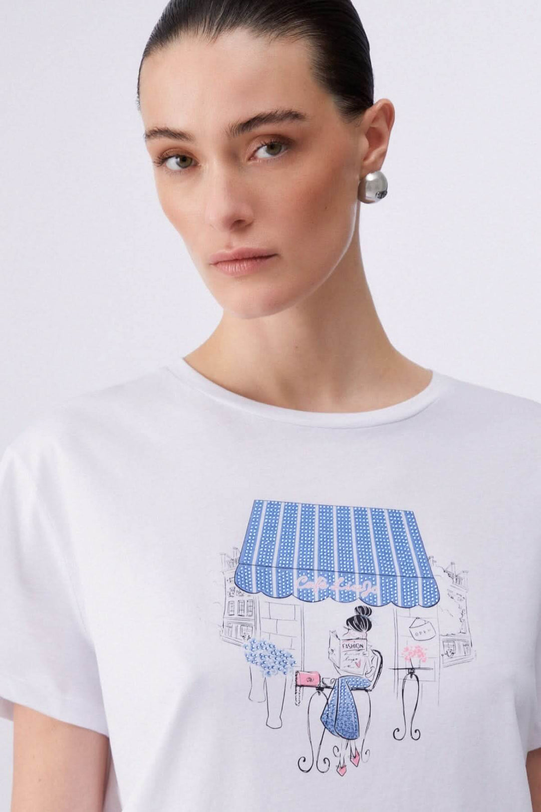T-shirt à manches courtes avec imprimé graphique de femme assise sous une marquise bleue, style moderne et décontracté.