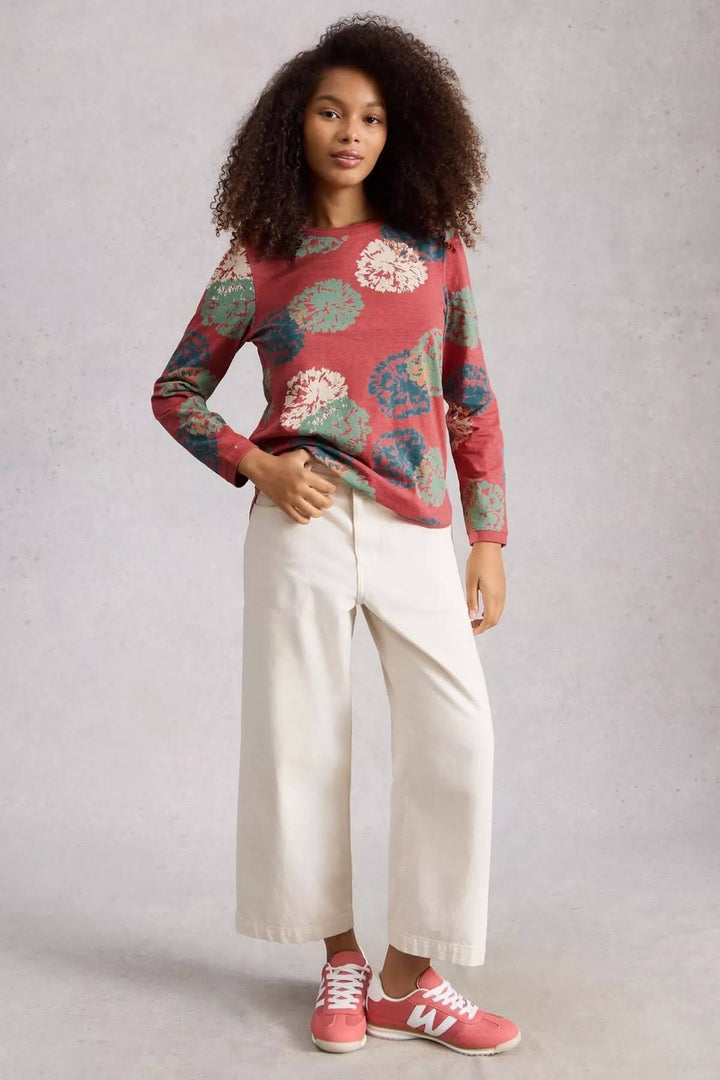 Femme portant un T-shirt à manches longues Clara avec motif, coupe droite et pantalon blanc, confort parfait pour le quotidien.