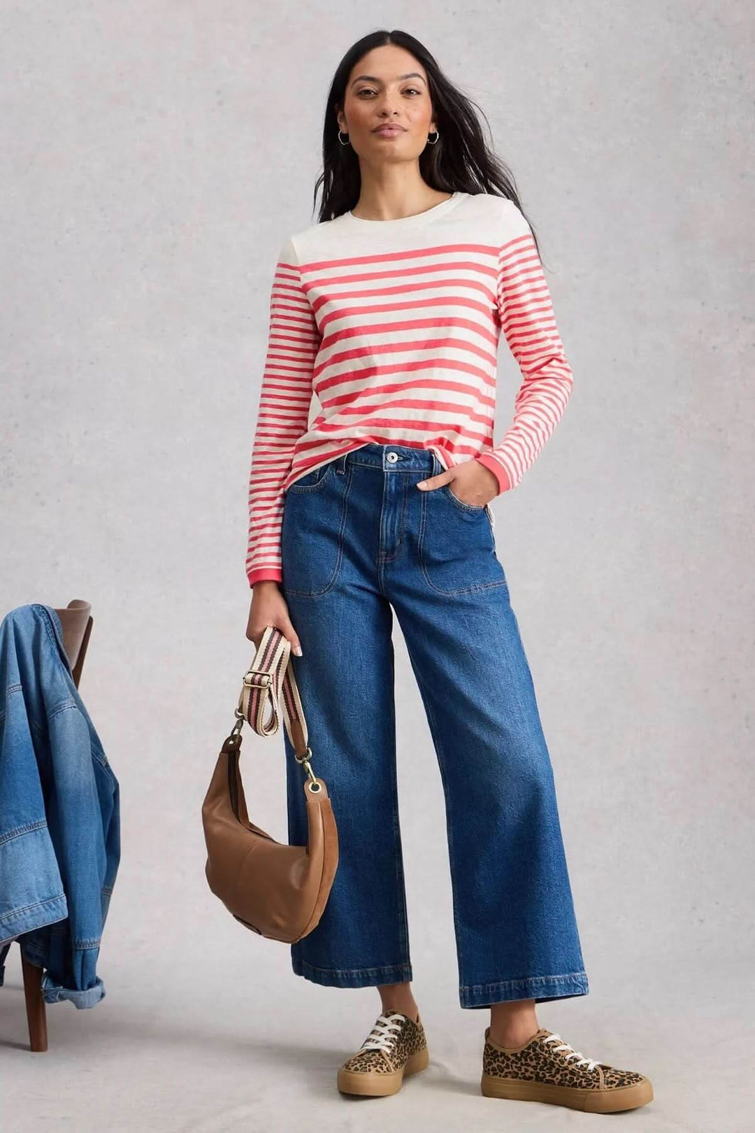 Femme portant un t-shirt rayé à manches longues avec un jean, sac à main marron, et chaussures léopard, style décontracté parisien.