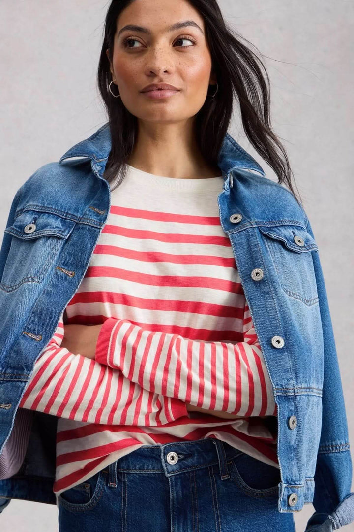 Femme portant un T-shirt rayé à manches longues avec une veste en jean sur les épaules.