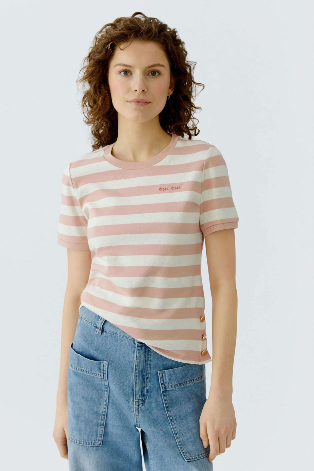 Femme portant un T-shirt à rayures avec détails décoratifs sur le côté, coupe droite et encolure ronde.