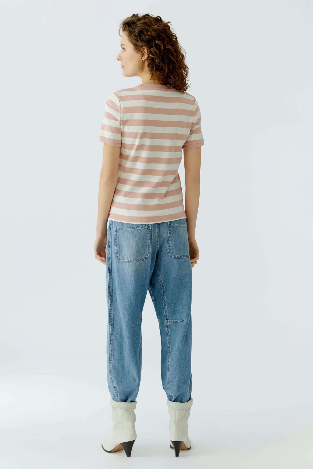 Femme portant un t-shirt à rayures roses et blanches avec une coupe droite et manches courtes.