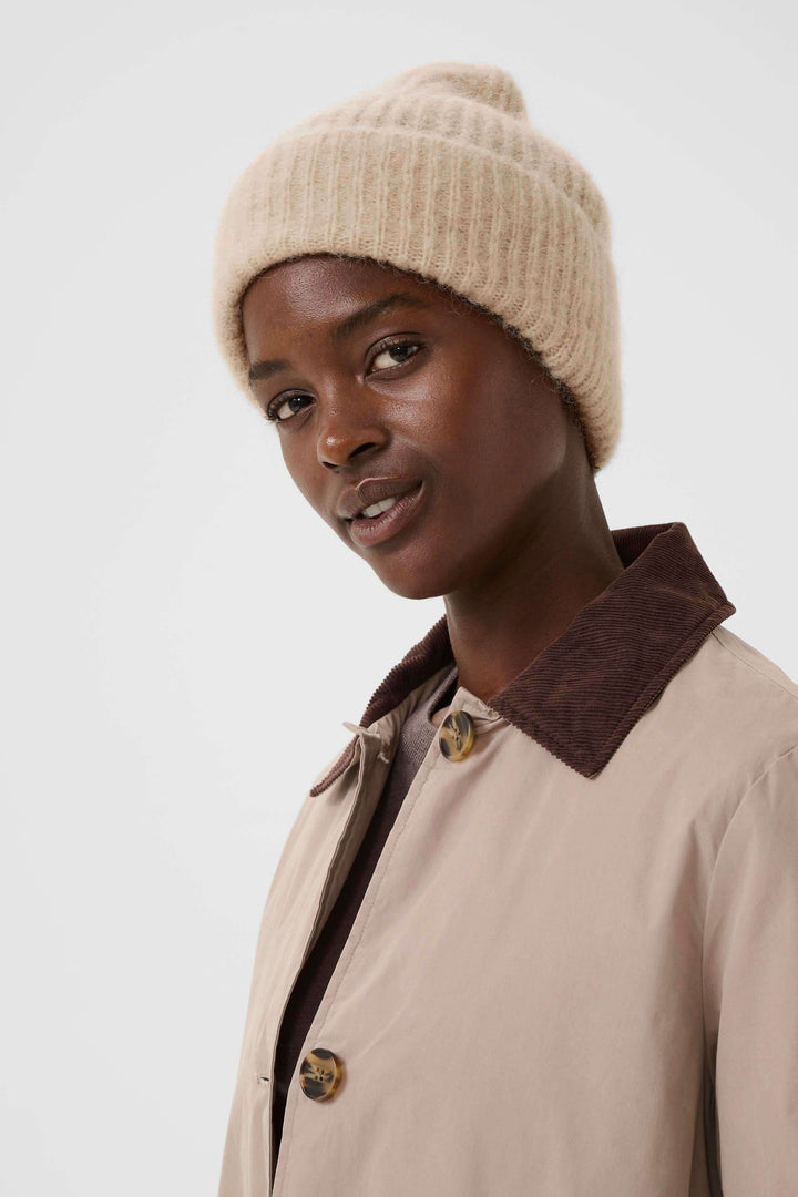 Tuque Sanja en tricot côtelé beige portée par un modèle, mettant en avant sa douceur et sa coupe moderne, style urbain décontracté.