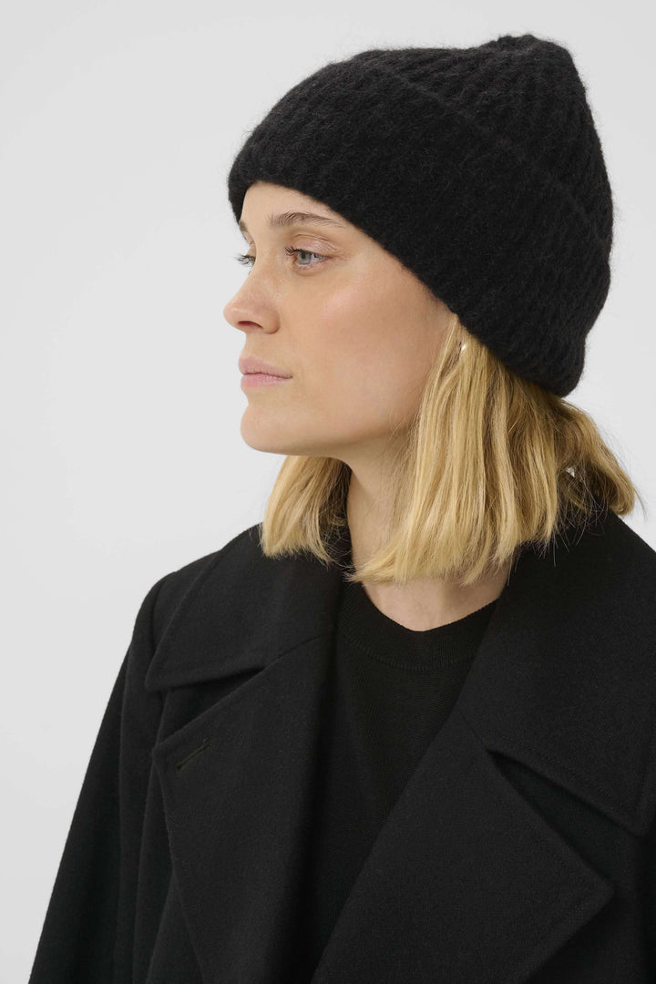 Femme portant la Tuque Sanja en tricot côtelé noir, style hivernal moderne.